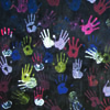 Painted handprints in white, green, blue, purples, red and pink on dark background
