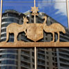 Australian Coat of Arms made from metal mounted on window; reflection of multi-story building in background
