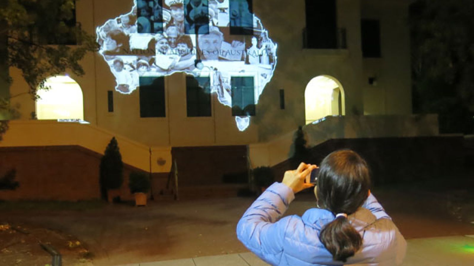 Masters student Gabriela Vayas Rodriguez films the test projection of her digital animation projection on the façade of the National Archives of Australia. Image: supplied.