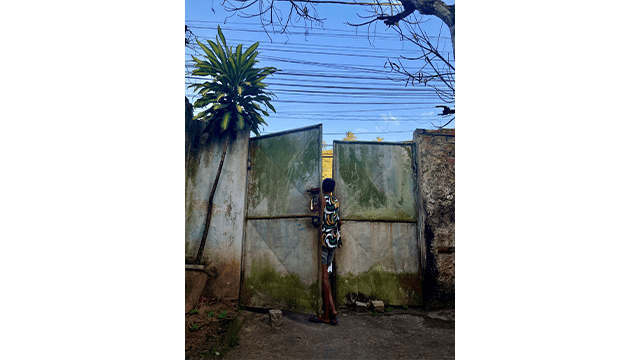 A child looks through a metalic door in Salvador di Bahia, Brazil